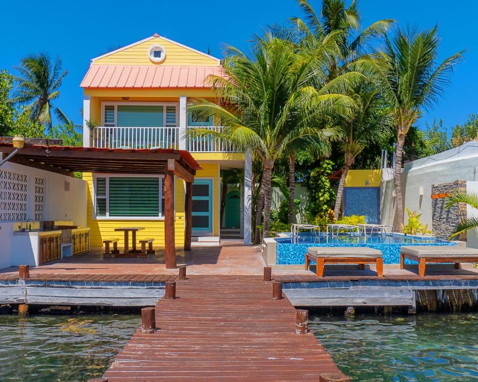 a house on the water with a wooden dock at Villas Comodoro in Isla Mujeres