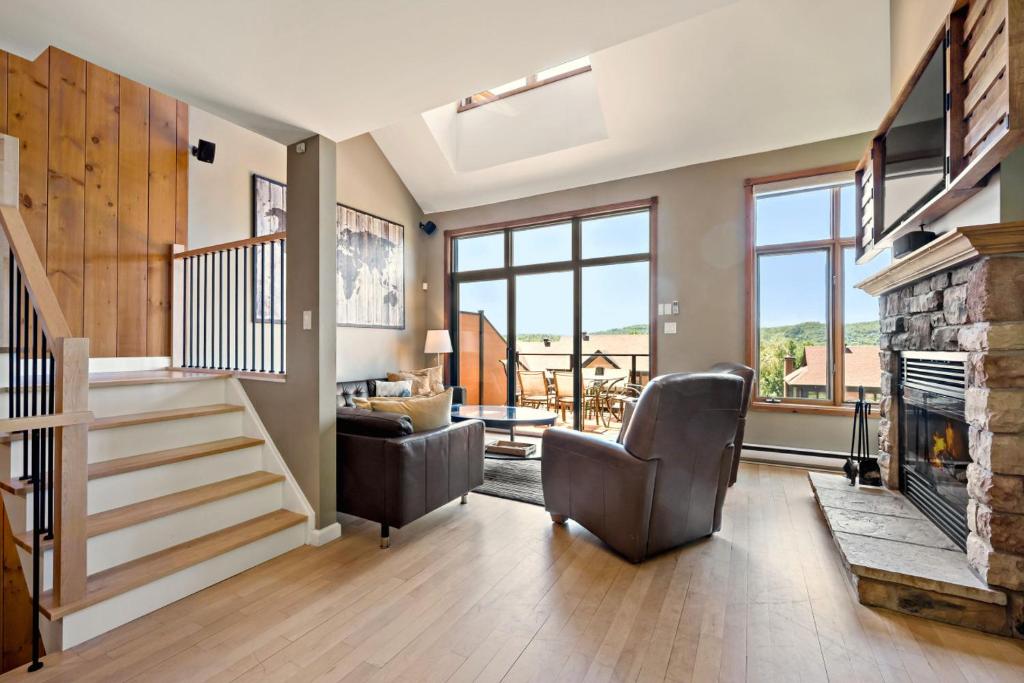 a living room with a staircase and a fireplace at Tremblant Prestige - Clairiere 406 in Mont-Tremblant