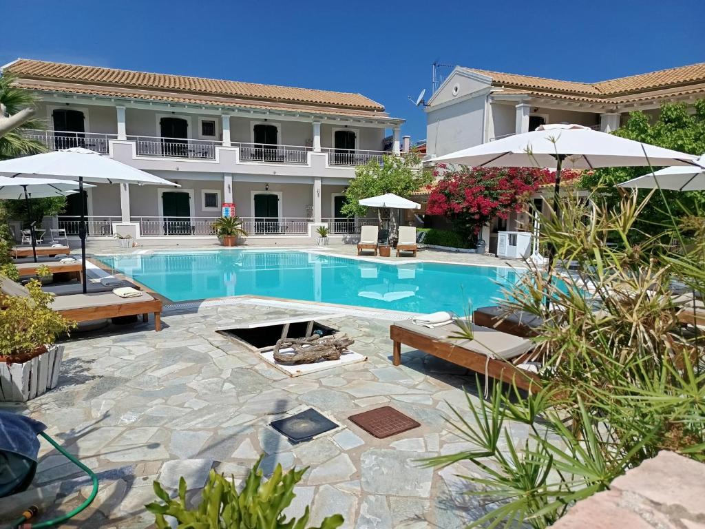 a swimming pool with benches and umbrellas next to a building at Toni´s Guesthouse in Kavos