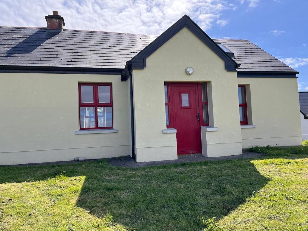 a small white house with a red door at Callacoon Cottage in Louisburgh
