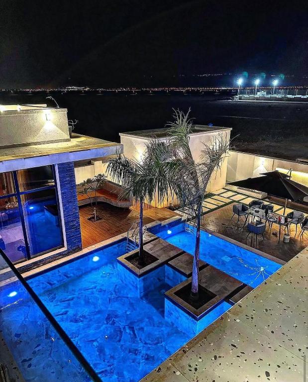 a swimming pool with two palm trees on top of a building at The W Luxury Chalet in Salalah