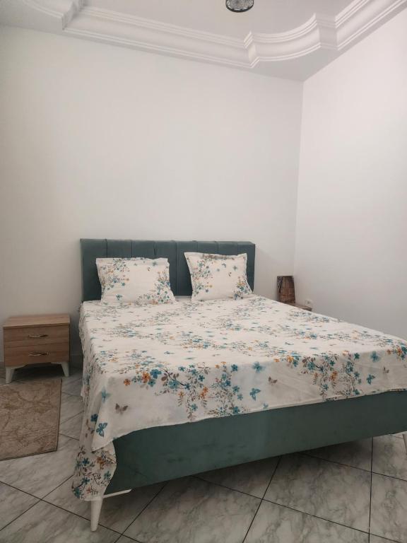 a bedroom with a bed with a floral comforter and pillows at Location saisonnière entre mer, forêt et calme in Raʼs al Jabal