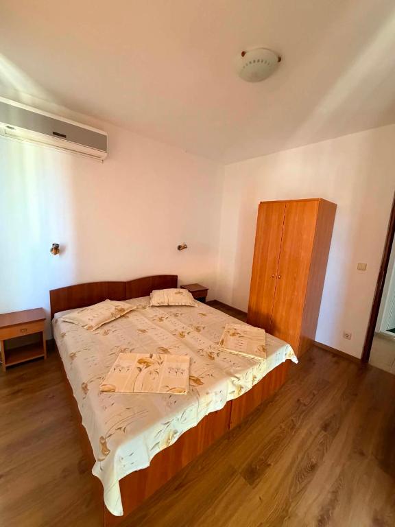 a bedroom with a large bed with a wooden floor at Guest House Dayana Apartment 2 in Ravda