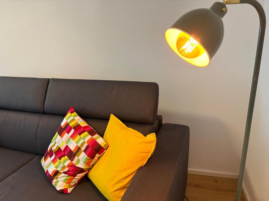 a lamp next to a couch with two pillows at VITA Apartment in Herrenberg