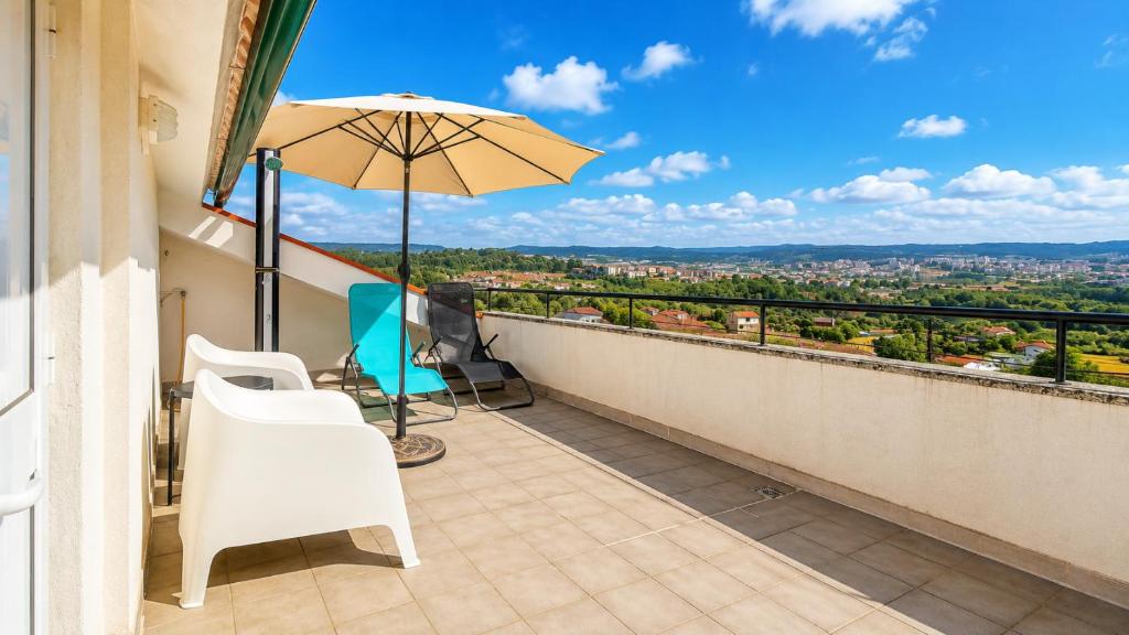 a balcony with a table and chairs and an umbrella at Casa Machado in Vila Real