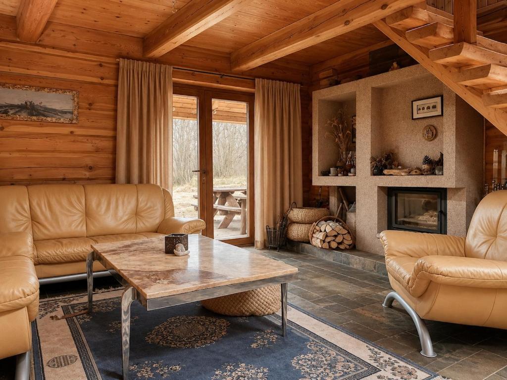a living room with a table and leather furniture at Kāpas Wood house in Uguņi