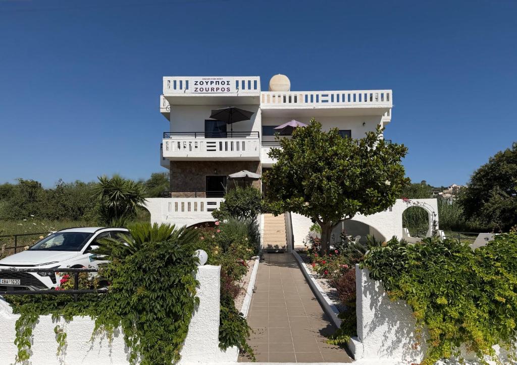 a white building with a car parked in front of it at Zourpos Studios in Kalyves