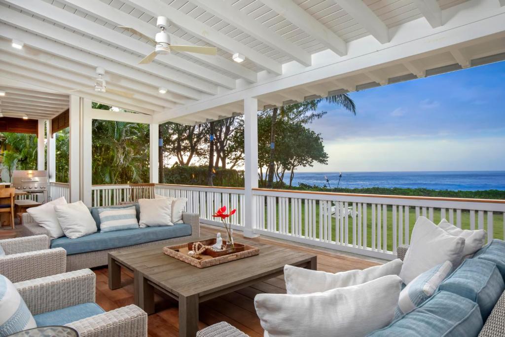 a porch with couches and a table and the ocean at Lei Ali'i in Haleiwa