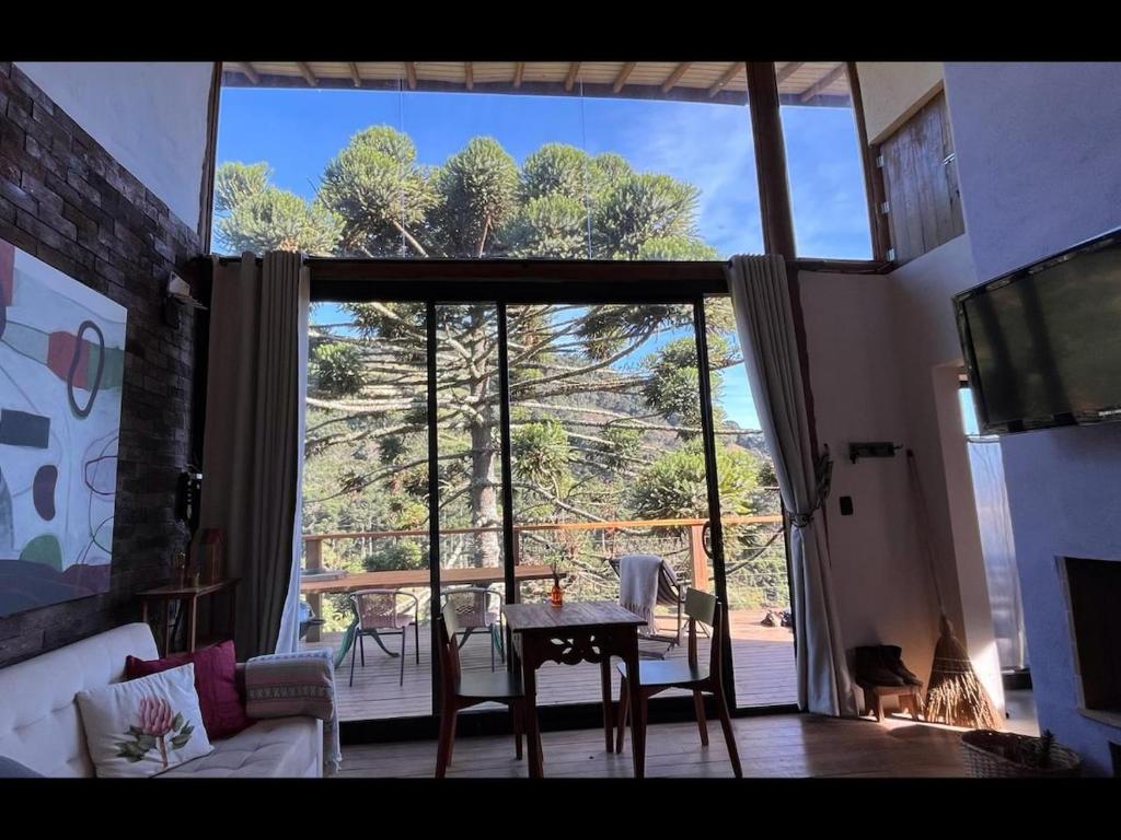 a living room with a table and a large window at Chalé Roxo na Araucária in Gonçalves