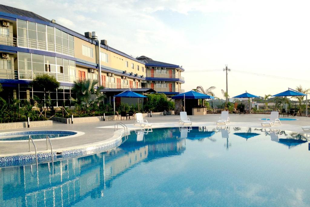 uma grande piscina com cadeiras brancas e um edifício em Hotel Olga Lucia em Barrancabermeja