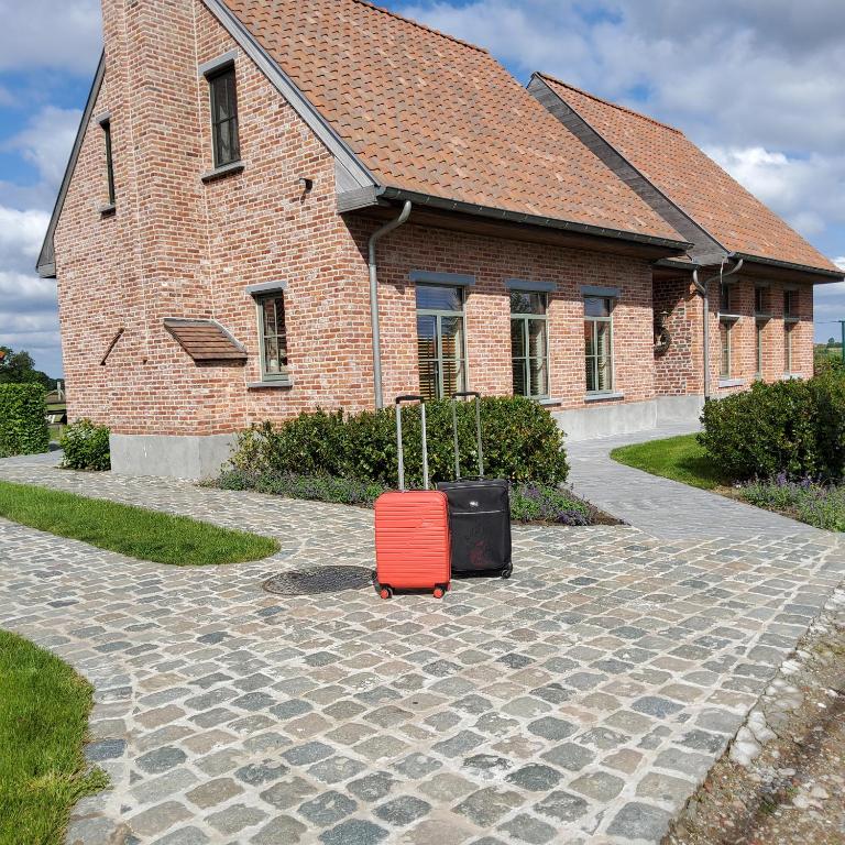 a red suitcase sitting in front of a brick building at Vakantiewoning Maison Chaperon in Wervik