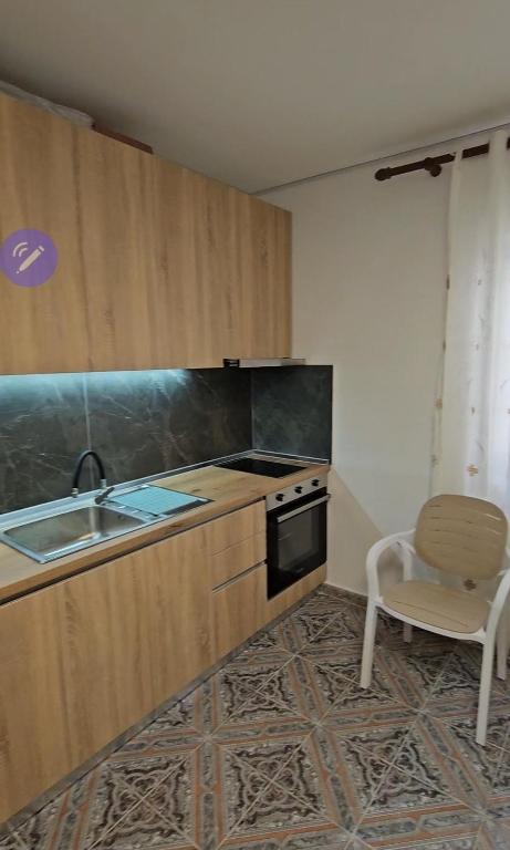 a kitchen with a sink and a stove and a chair at Daja's Guest House in Shëngjin