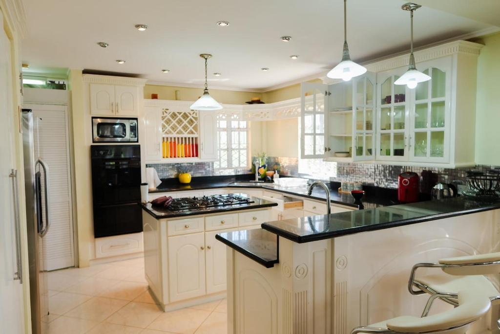 a large kitchen with white cabinets and black appliances at Cap Estate Ocean View Villa, Gros Islet, St Lucia in Dame de Traversay