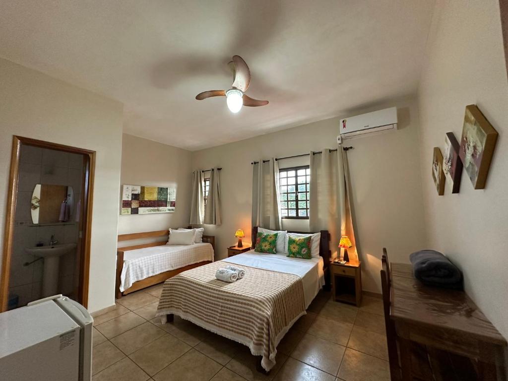 a bedroom with two beds and a window at Chico de Sá Pousada in Pirenópolis