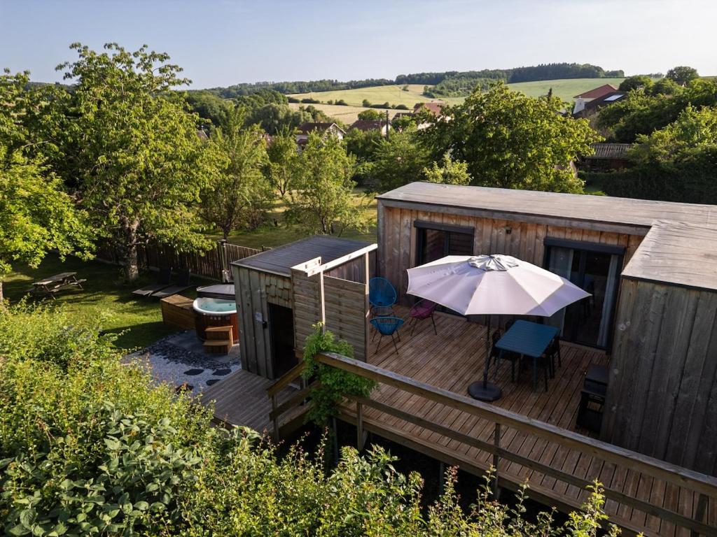 a deck with an umbrella and chairs on it at Gîte de la Bridolée, sauna et bain nordique in Lorquin