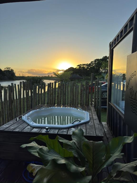 a bath tub sitting on a table with a sunset in the background at Refúgio do Lago in Linhares