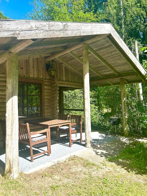 a wooden pavilion with a wooden table and benches at Löydön Kartano Camping in Mikkeli