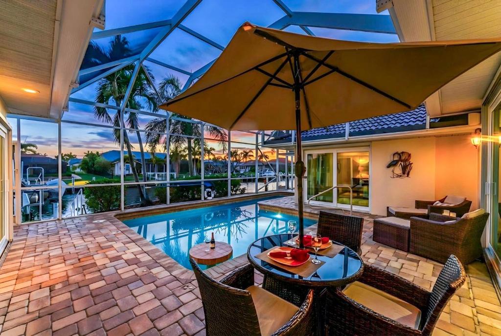 a house with a pool and a table with an umbrella at Villa Hibiscus-Waterfront-Free Heated Pool-Dock-Bikes-Other Amenities in Punta Gorda