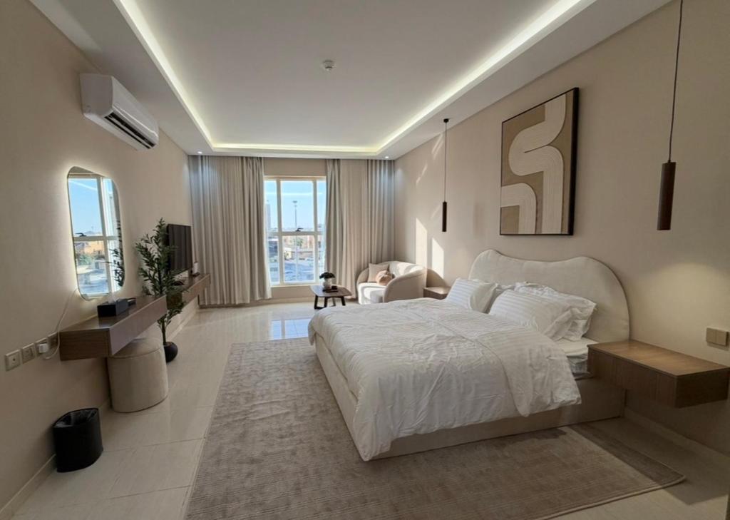 a bedroom with a large white bed and a television at لينك هوم استديو فندقي دخول ذاتي in Buraydah