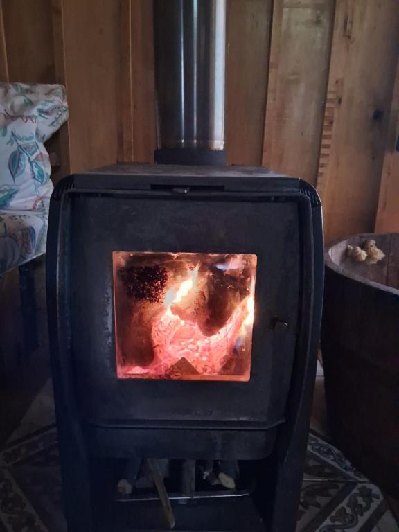 a black stove with a fire inside of it at Refugio de la Montaña 2 personas in Coñaripe