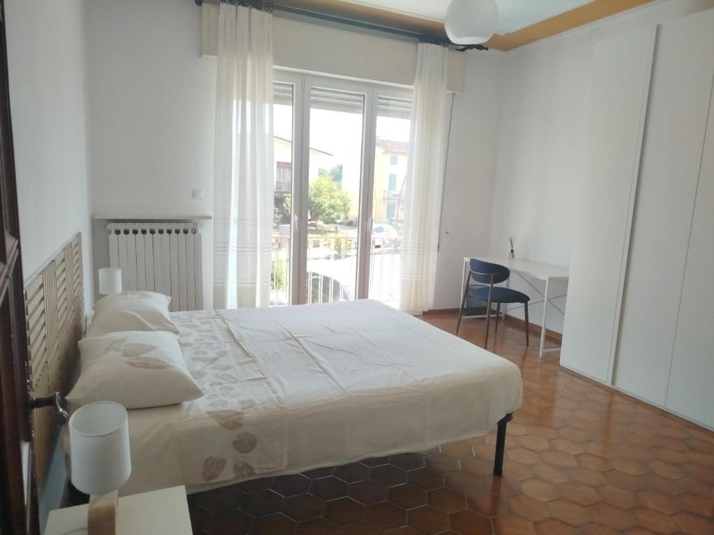 a white bedroom with a bed and a desk and a window at Camera matrimoniale Capannori, Lucca in Capannori
