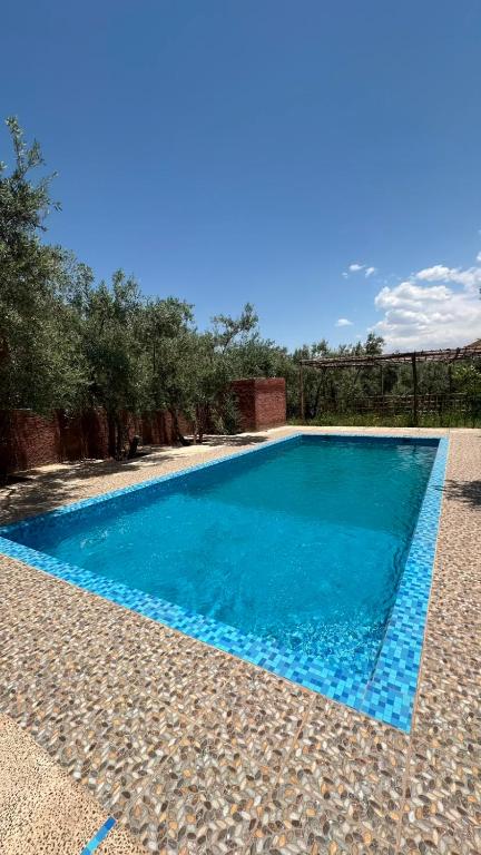 a swimming pool with blue water in a backyard at Tissi House in Tahannout
