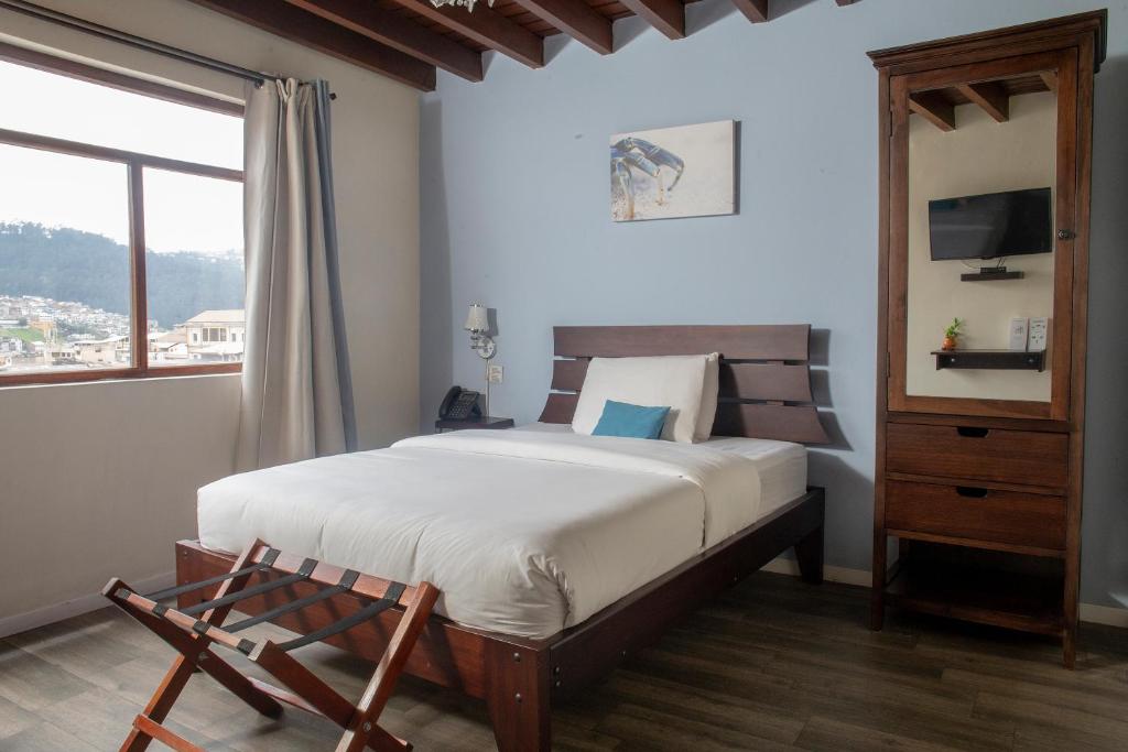 a bedroom with a large bed and a window at Hotel Colonial San Agustin in Quito