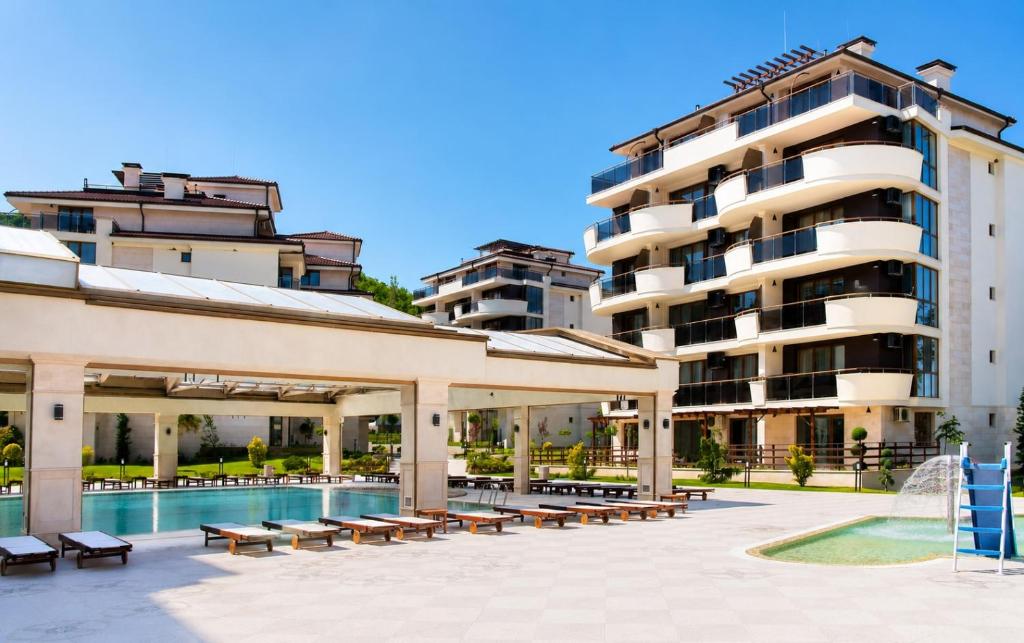 a hotel with a pool and benches and a building at Boutique 1BR | Long Beach Sea View Next to the Beach in Shkorpilovtsi