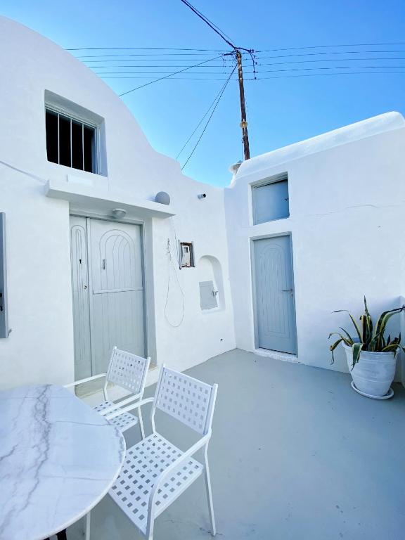 a patio with two chairs and a table and a building at Argonaut House in Anafi