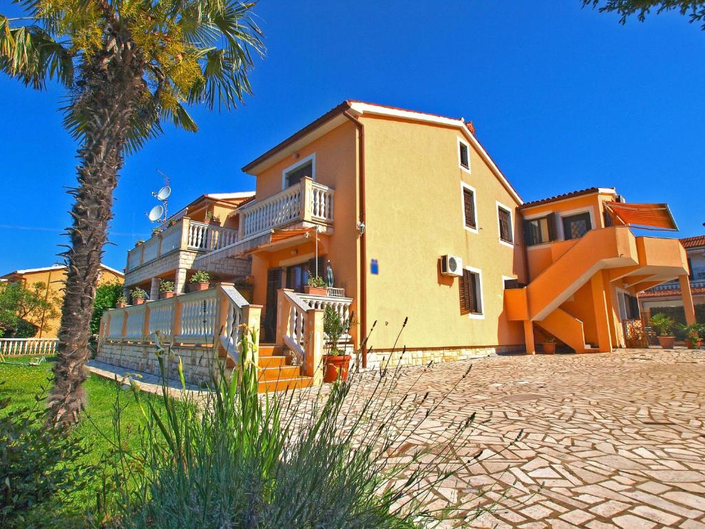 ein großes Haus mit einer Palme davor in der Unterkunft Apartments Orange 768 in Fažana