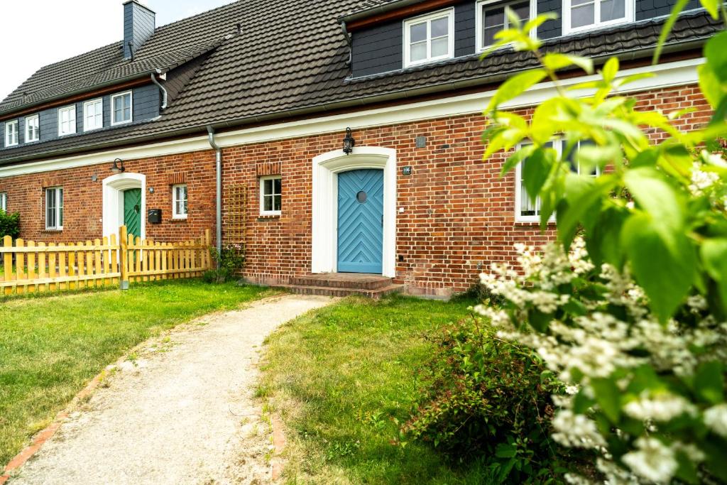 a brick house with a blue door and a driveway at Ferienhaus WalnutCottage in Rechlin