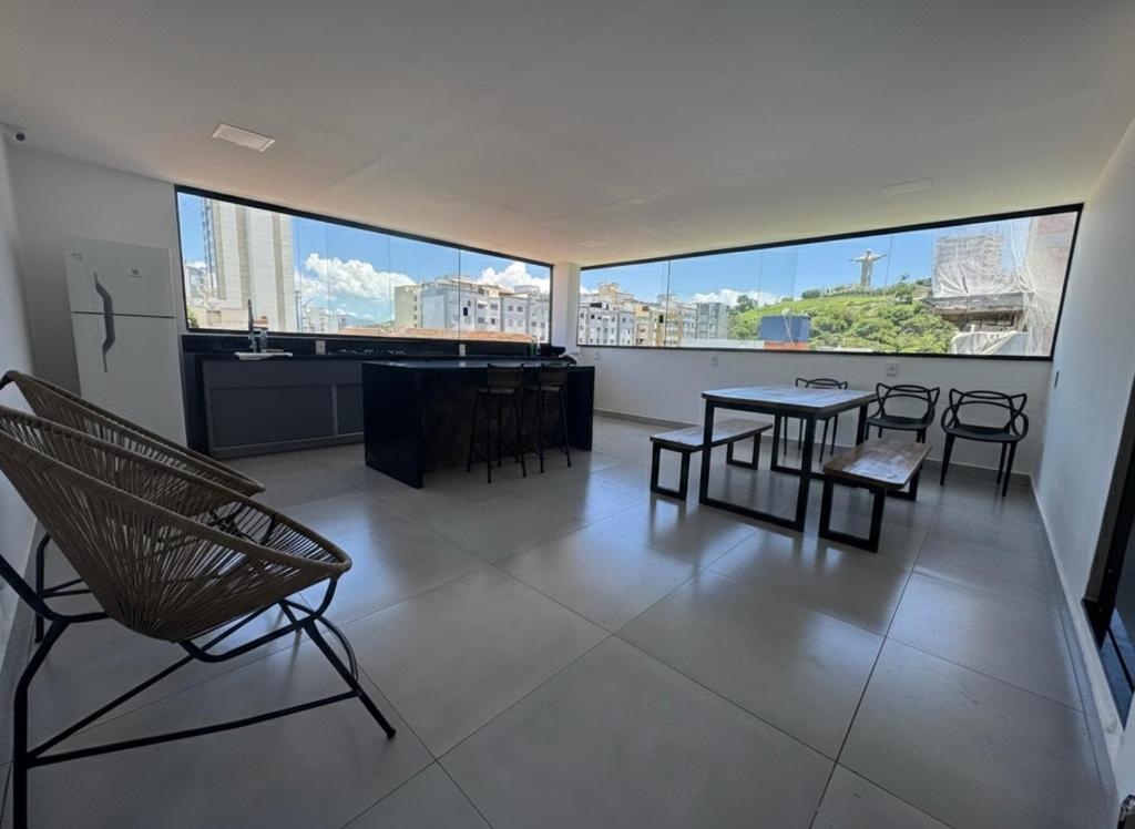 a room with a table and chairs and a large window at Oásis urbano in Muriaé