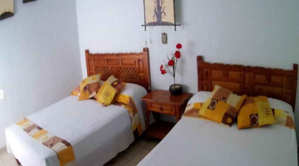a bedroom with two beds and a table with flowers at Quinta Belu Oaxtepec in Oaxtepec