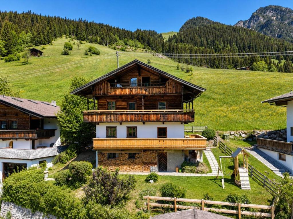 a large wooden house on a hill with mountains at Tirola Hütte in Alpbach