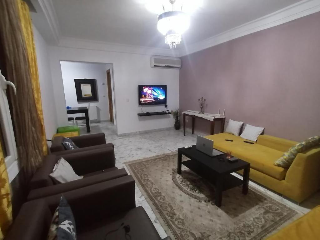 a living room with a yellow couch and a tv at Appartement S3 Haut Standing 141m2 Connecté avec Fibre - 7-10 min Aéroport in Burj at Turkī