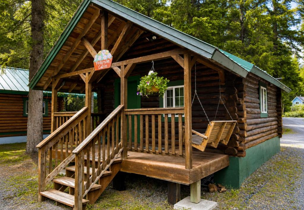 a log cabin with a porch and a porch swing at Box Canyon Cabins in Seward