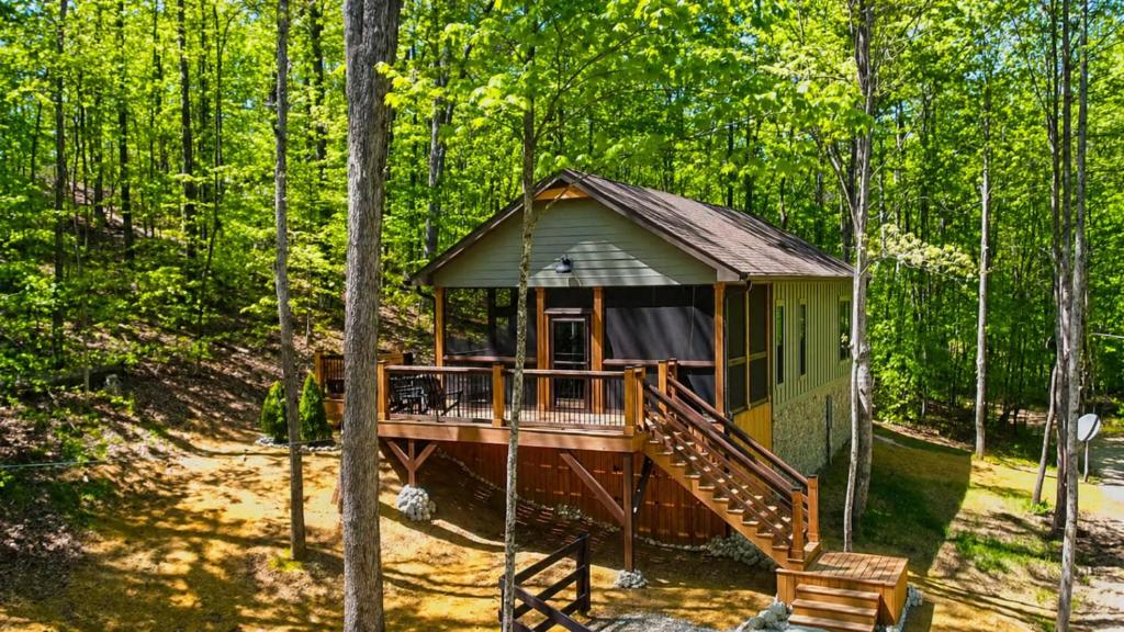 a cabin in the woods with a porch and a deck at Hot Tub Cabin + Screened Porch | Red River Gorge in Beattyville