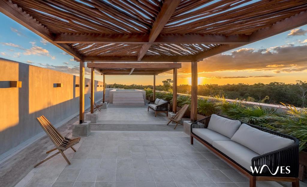 a patio with a couch and chairs on a building at Villa morada in Tulum