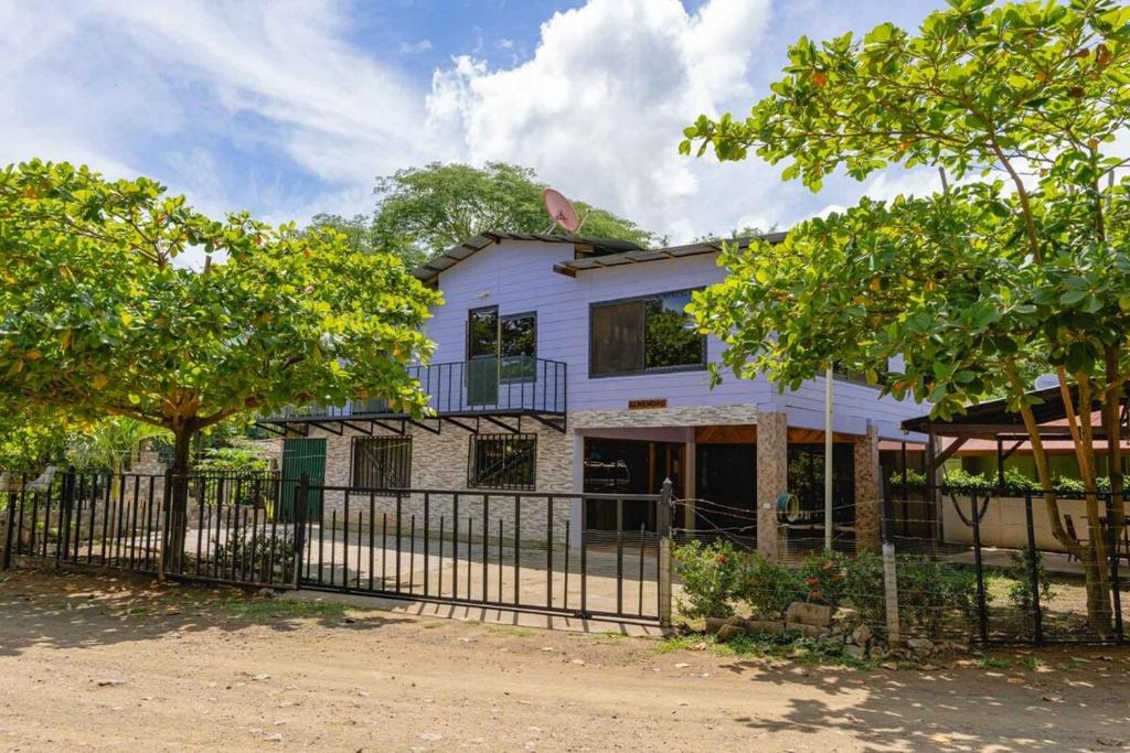 a white house with a fence and trees at Almendro house playa Panamá in Playa Panama