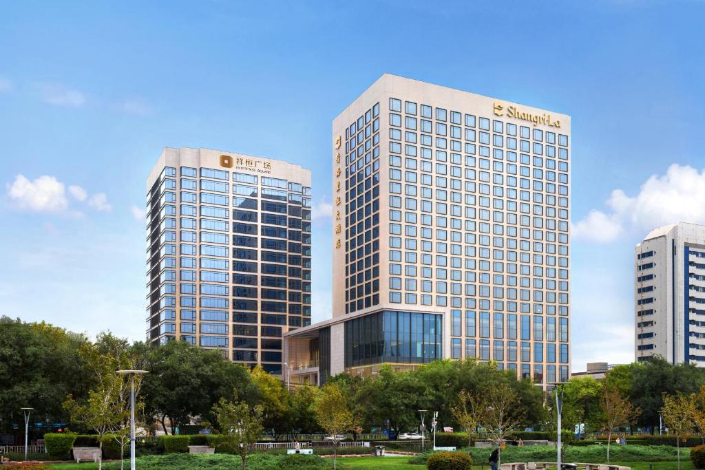 two tall buildings in a city with trees in front at Shangri-La Jinan in Jinan