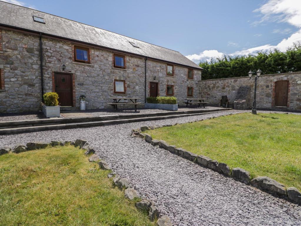 a stone building with a grassy yard in front of it at Beudy Bach in Abergele