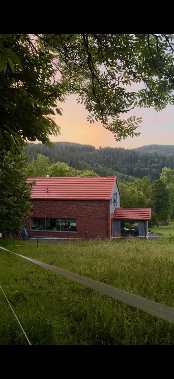a brick building with a red roof in a field at SalviaMontis in Kamienna Góra