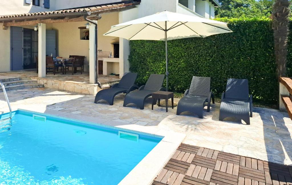 a pool with chairs and an umbrella next to a house at Lukas-Gologorica in Gologorica