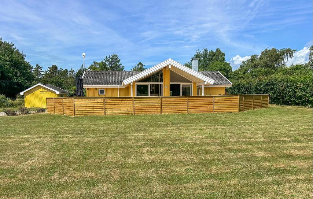 a yellow house with a wooden fence in a yard at Holiday Home Laxtonvej Humble in Humble