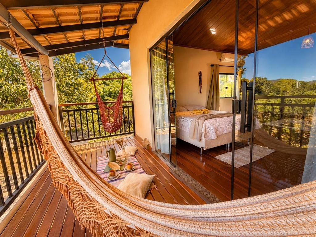 a hammock in a room with a bed on a balcony at Chalé Baru - Ar-cond - Varanda Pôr do Sol - Cavalcante Goiás in Cavalcante