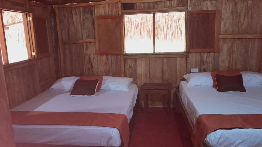 two beds in a small room with two windows at Villa Neluc in San Bernardo del Viento