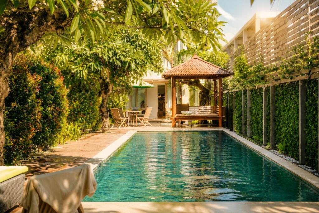 a swimming pool with a gazebo next to a building at D'sawah Villa in Tanah Lot