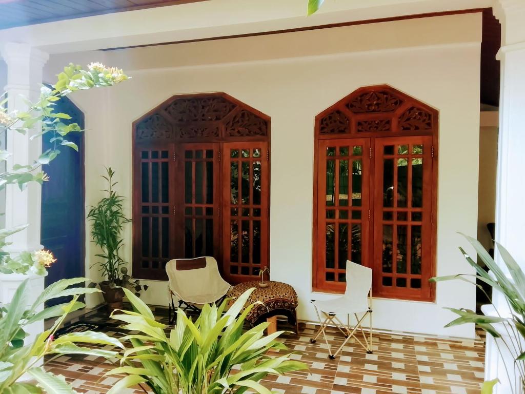 a porch with two wooden doors and chairs and plants at Luuna'S Hostel Sigiriya in Sigiriya