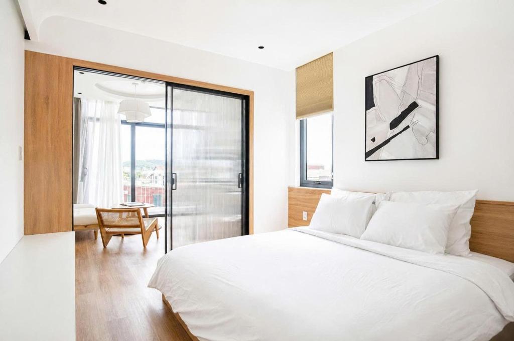 a bedroom with a white bed and a sliding glass door at Adory Homestay Huế in Hue