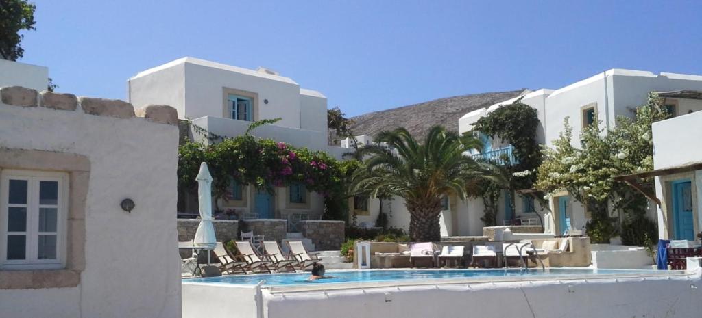 un complejo con piscina, sillas y un edificio en Ampelos en Chora Folegandros